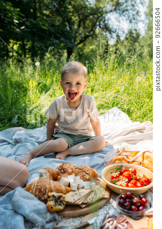 Boy child preschooler on a picnic. Smiles, eating cherries and enjoying summer. 92666504