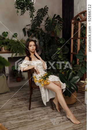 Beautiful girl in a dress sits on a chair 92666712