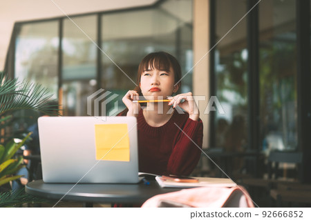 Young adult asian college student woman with laptop for study at cafe on winter day. 92666852