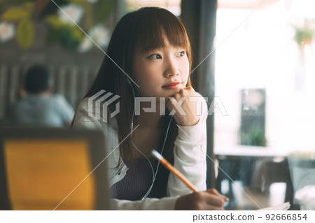 Young adult asian college student woman using laptop study and work online at cafe. 92666854