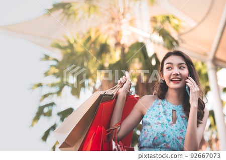 Adult asian woman shopping using smartphone talk with friend. Adult asian woman shopping using smartphone talk with friend. 92667073