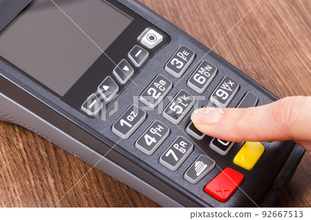 Payment terminal and finger entering PIN code. Credit card reader using for cashless paying 92667513