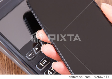 Mobile phone or smartphone with payment terminal. Credit card reader. Cashless paying for shopping 92667514