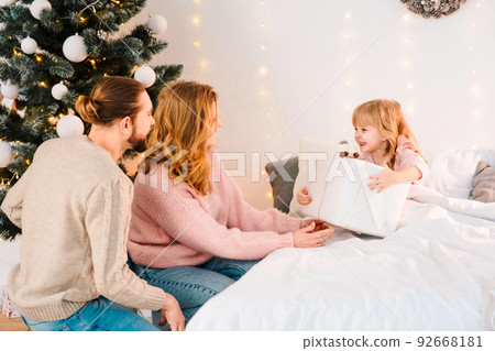 Little girl takes Christmas gift boxes from her parents 92668181