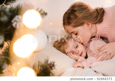 Mom kisses sleeping daughter on christmas morning 92668373