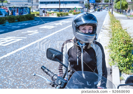 A smiling female rider touring Yokohama on a large American motorcycle A smiling female rider touring Yokohama on a large American motorcycle 92668690