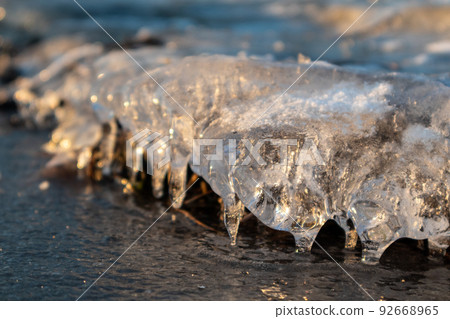 Clear ice icicle close-up sparkling on frozen lake 92668965