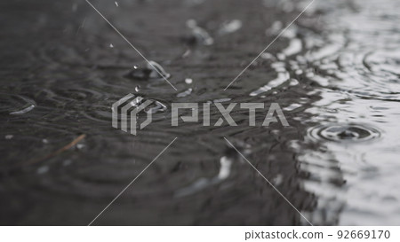 closeup of summer heavy rain drops falling into puddles on asphalt 92669170