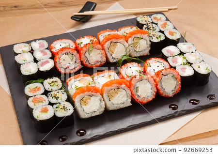 a large set of sushi rolls on a black stone plate a large set of sushi rolls on a black stone plate 92669253