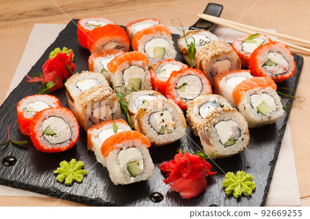 a large set of sushi rolls on a black stone plate 92669255