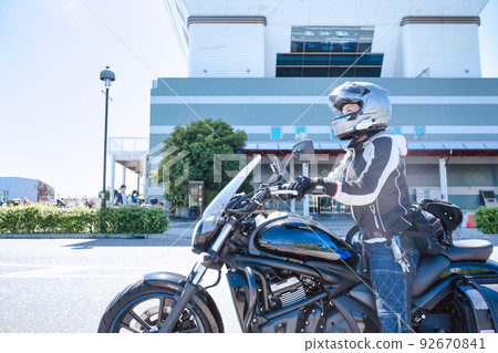 A smiling female rider touring Yokohama on a large American motorcycle 92670841