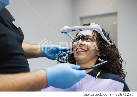 Doctor orthodontist installs a system for diagnosing jaw joints and occlusion for a woman patient. Modern dental equipment Doctor orthodontist installs a system for diagnosing jaw joints and occlusion for a woman patient. Modern dental equipment 92671285