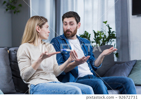 Sad man and woman sitting on the couch, disappointed with a negative pregnancy test Sad man and woman sitting on the couch, disappointed with a negative pregnancy test 92672731