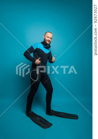 Man in diver wear holding thumb up on blue background 92673027