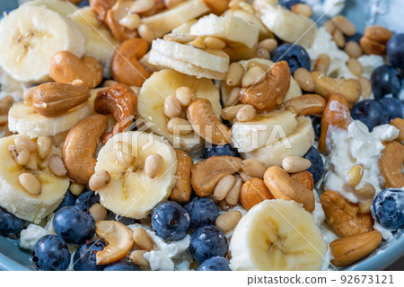 Beautiful breakfast - cottage cheese, berries cashew, cedar, blueberry and honey in the plate. Good morning. 92673121