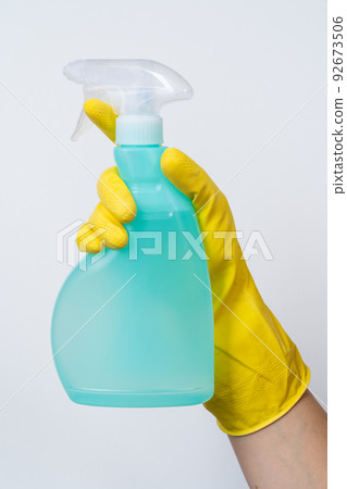 Cleaning concept - hand in yellow cleaning gloves holds spray bottle Cleaning concept - hand in yellow cleaning gloves holds spray bottle 92673506