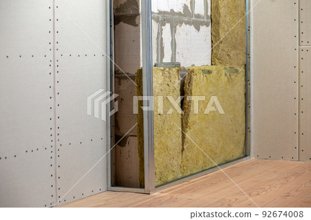 Wall of a room under renovation with mineral rock wool insulation and metal frame prepared for drywall plates. Wall of a room under renovation with mineral rock wool insulation and metal frame prepared for drywall plates. 92674008