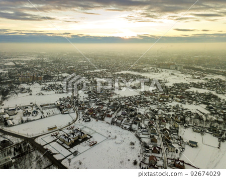 Top view of city suburbs or small town nice houses on winter morning on cloudy sky background. Aerial drone photography concept. Top view of city suburbs or small town nice houses on winter morning on cloudy sky background. Aerial drone photography concept. 92674029
