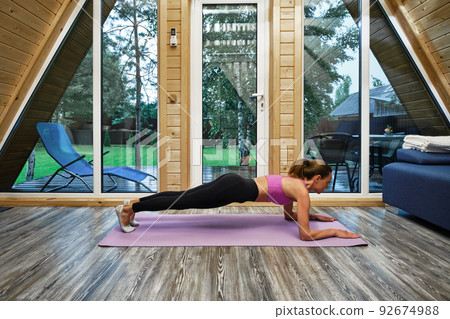 Sportive woman does plank exercise in forest house 92674988