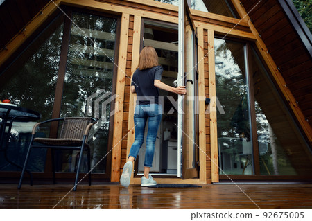 Woman enters forest cabin, back view Woman enters forest cabin, back view 92675005