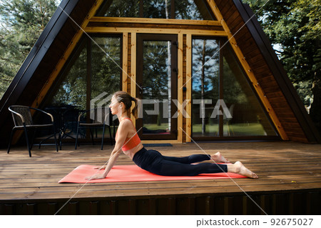 Young woman does snake or cobra pose outdoors Young woman does snake or cobra pose outdoors 92675027
