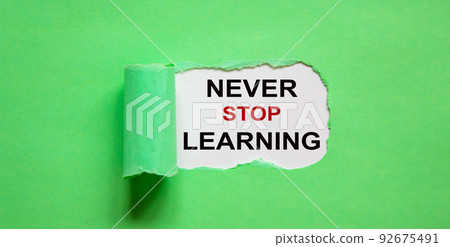 The text 'never stop learning' appearing behind torn green paper. 92675491