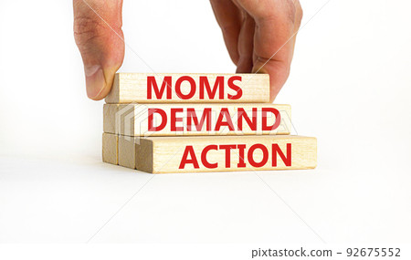 Moms demand action symbol. Concept words Moms demand action on wooden blocks on a beautiful white table white background. Businessman hand. Business, finacial and Moms demand action concept. 92675552