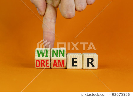 Winner or dreamer symbol. Concept words Winner or dreamer on wooden cubes. Businessman hand. Beautiful orange table orange background. Business and Winner or dreamer concept. Copy space. 92675596