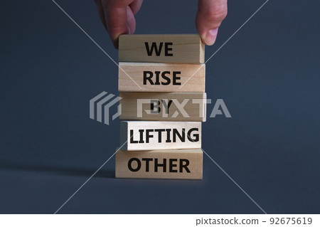 We rise by lifting other symbol. Concept words We rise by lifting other on wooden blocks. Businessman hand. Beautiful grey background. Business we rise by lifting other concept. Copy space. 92675619