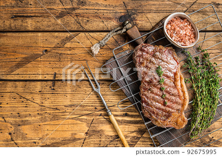 Grilled striploin or New York beef meat steak cooked on BBQ. Wooden background. Top view. Copy space 92675995