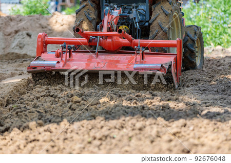 Cultivator for a mini-tractor for loosening the soil. Agricultural work. Excavation. Close-up Cultivator for a mini-tractor for loosening the soil. Agricultural work. Excavation. Close-up 92676048