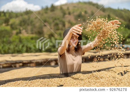 Pretty young lady throwing coffee beans up outdoors at farm Pretty young lady throwing coffee beans up outdoors at farm 92676278