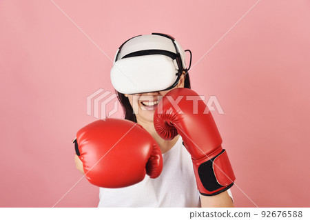 Asian woman hitting a punch by vr glasses, Working out with boxing video games 92676588