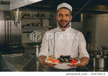 Portrait of cheerful chef standing with cooked traditional japanese sushi 92676613
