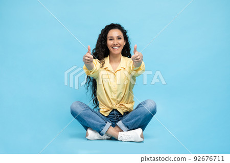 Arabic Woman Gesturing Thumbs Up With Both Hands, Blue Background Arabic Woman Gesturing Thumbs Up With Both Hands, Blue Background 92676711