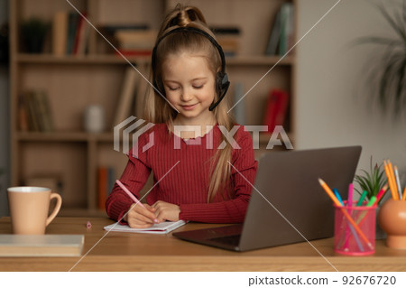 Kid Girl Learning Online Using Laptop Doing Homework At Home 92676720