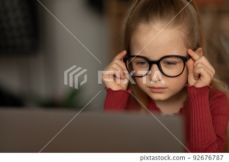 Kid Girl Squinting Eyes Wearing Glasses Looking At Laptop Indoors 92676787