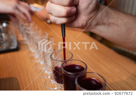 Bartender pouring strong alcoholic drink into small glasses on bar, shots. Bartender pouring strong alcoholic drink into small glasses on bar, shots. 92677672