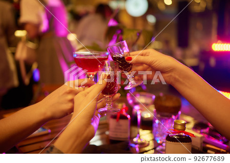 people at the bar try tinctures, red tinctures in glasses, alcoholic shots. 92677689