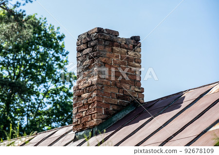 Old brick chimney in need of repair on a roof. Heating and fire safety concept 92678109