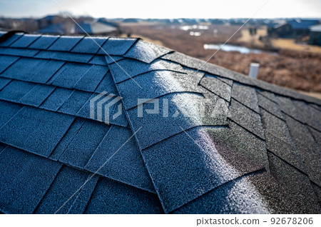 Contrast of frost line on a shingle roof as the sun rises and melts it Contrast of frost line on a shingle roof as the sun rises and melts it 92678206