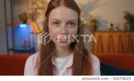 Close-up of happy beautiful young redhead child girl smiling looking at camera at home on couch Close-up of happy beautiful young redhead child girl smiling looking at camera at home on couch 92678620
