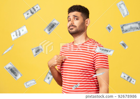 This is rich man. Portrait of arrogant self-confident man pointing at chest, looking proud and egoistic. money falling and he is rich. indoor studio shot isolated on yellow background This is rich man. Portrait of arrogant self-confident man pointing at chest, looking proud and egoistic. money falling and he is rich. indoor studio shot isolated on yellow background 92678986
