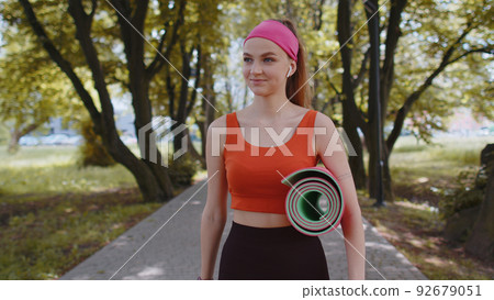 Athletic fitness sport runner girl walking with sport yoga mat to do fitness stretching exercises 92679051