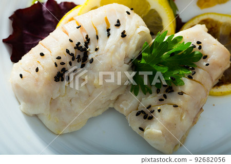 Cod prepared on steam, served at plate with greens and lemon Cod prepared on steam, served at plate with greens and lemon 92682056