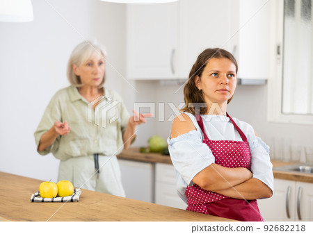 Upset girl at home kitchen while worried elderly mother reprimanding her. Family conflicts concept 92682218