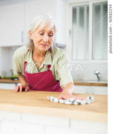 Mature woman cleaning kitchen table at home 92682254