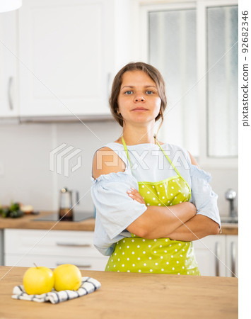 Housewife in apron with arms crossed in modern kitchen 92682346