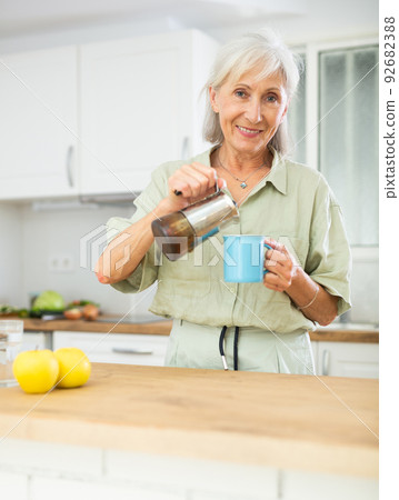 Cheerful senior woman pouring fresh coffee into mug 92682388
