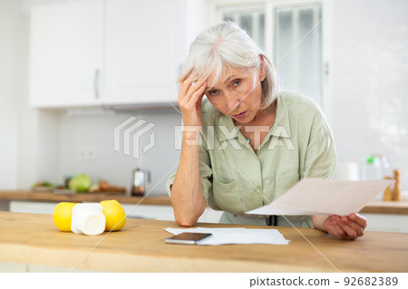 Senior woman analyzing bills at home 92682389